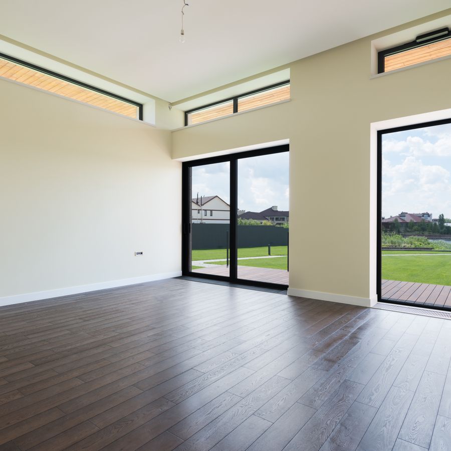 Bodentiefe Fenster in einem leeren Wohnraum mit Blick in den Garten