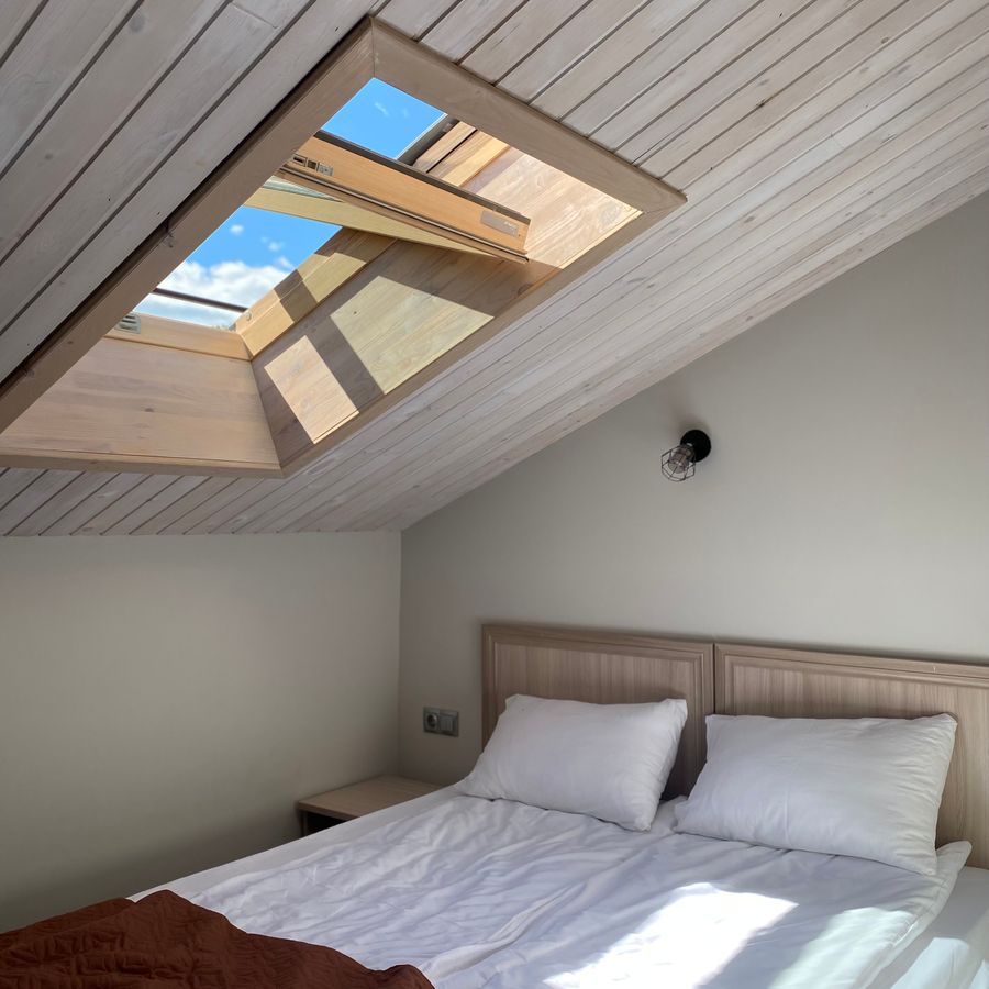 Dachfenster über einem Bett im ausgebauten Dachgeschoss