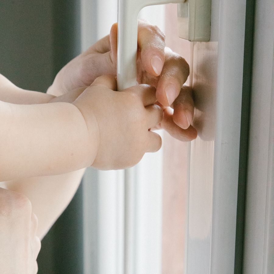 Hand an einem weißen Fenstergriff