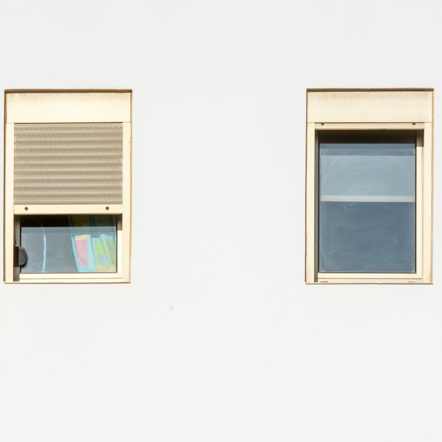 Rollläden an zwei Fenstern einer hellen Fassade
