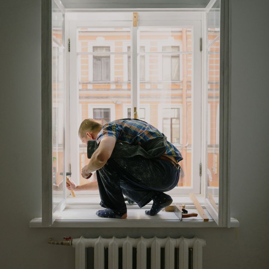Handwerker repariert ein Fenster von der Fensterbank aus
